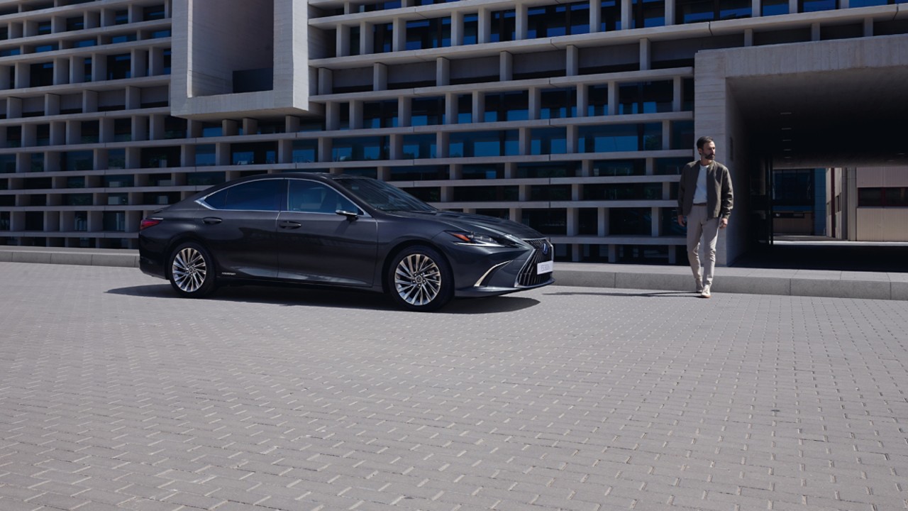 A man walking towards a parked Lexus ES