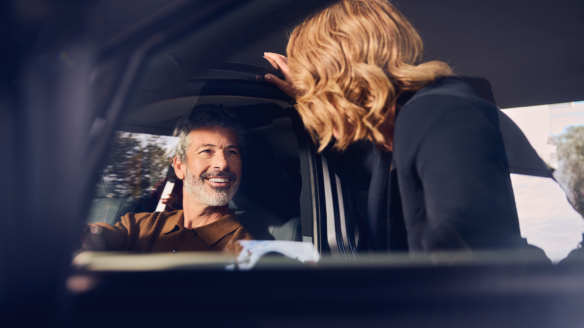 Un conducteur souriant à une personne debout, près d’une Lexus stationnée